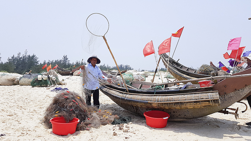 Một ngư dân bên những tay lưới bị hư hỏng do tàu giã cào gây ra