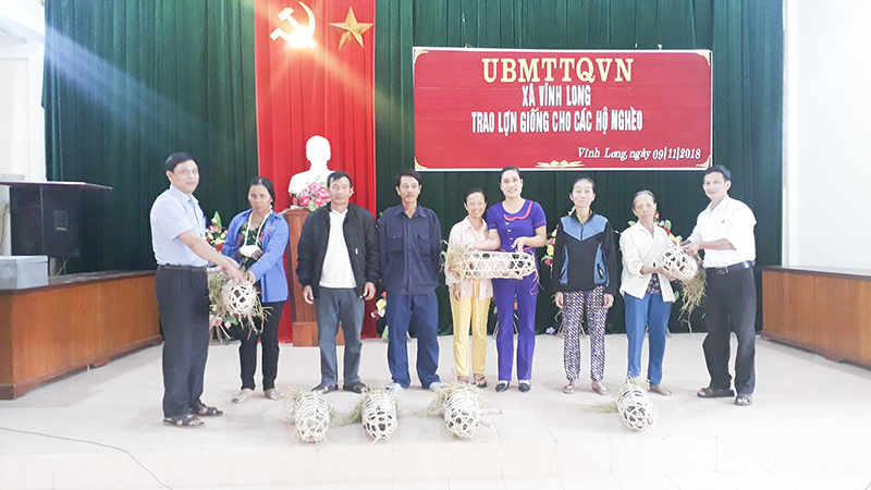 Lãnh đạo UBMTTQVN xã Vĩnh Long trao lợn giống cho các hộ nghèo