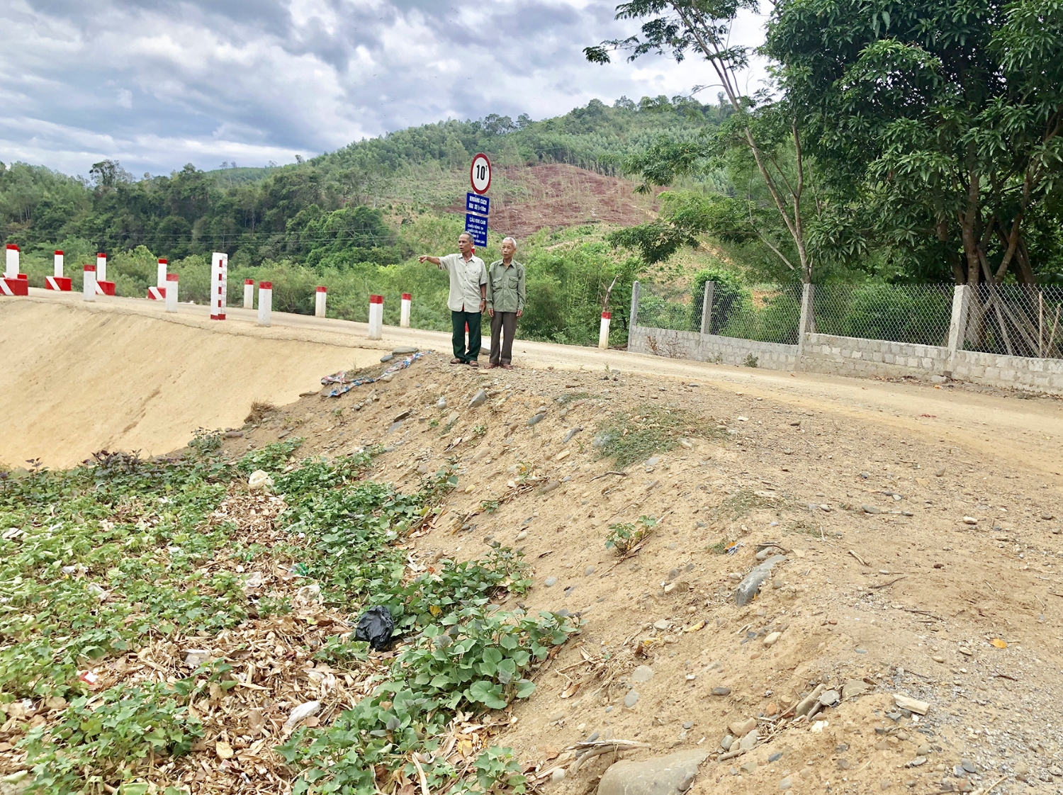 Ông Hồ Trọng Thuyết ( bên trái) đứng trên phần đất mà gia đình ông tự nguyện hiến để công trình cầu Khe Cam sớm hoàn thành và đi vào sử dụng