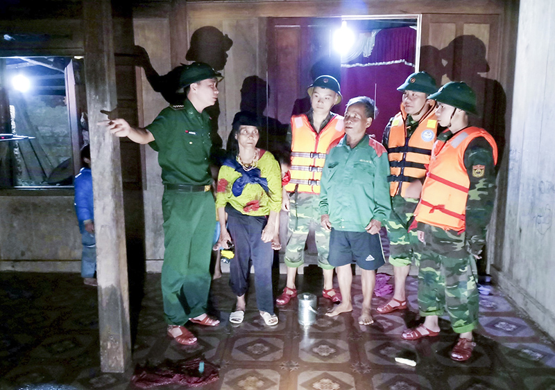 Dù đã nhận quyết định điều động công tác nhưng Đại úy Nguyễn Văn Bằng (đứng ngoài cùng, bên trái) vẫn nán lại cùng đồng đội giúp dân vượt qua mưa lũ