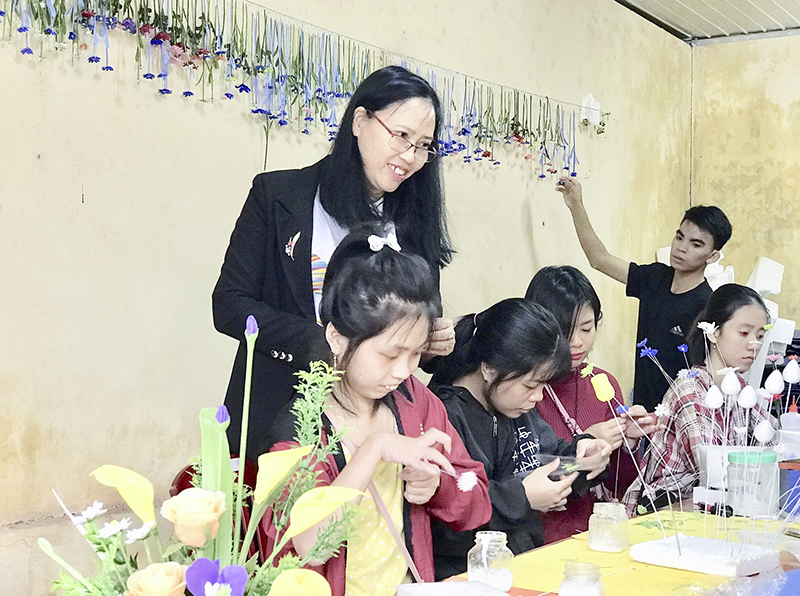 Cô giáo Cao Thị Yên bên các em học sinh khuyết tật trong giờ thực hành sản xuất hoa từ vật liệu đất sét và giấy​