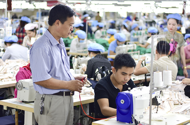 Anh Trần Quang Vinh (người ngồi mặc áo đen) bị khuyết tật nghe và nói được Công ty May Hòa Thọ - Đông Hà tạo việc làm ổn định với mức lương cao. Ảnh: TT