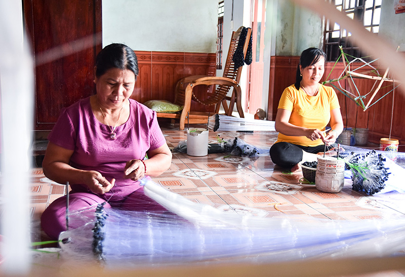 Những phụ nữ miệt mài công việc gắn phao vào lưới. Ảnh: T.T