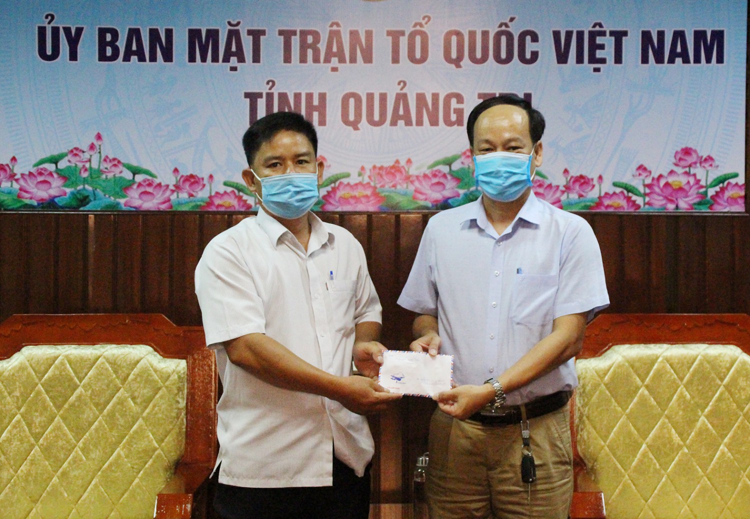 Phó Chủ tịch Ủy ban MTTQVN tỉnh Lê Hồng Sơn tiếp nhận khoản tiền ủng hộ của thầy Nguyễn Viết Tước (bên trái) - Ảnh: TÚ LINH