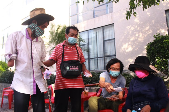 Ông Lê Quang Quỳnh (ngoài cùng bên trái) được một người bạn dắt đi bán vé số dạo ở TP. Đông Hà, Quảng Trị.