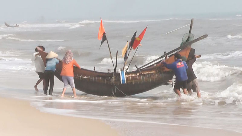 Ngư dân giúp nhau đưa thuyền lên bờ sau khi khai thác thủy sản trở về - Ảnh: LCT