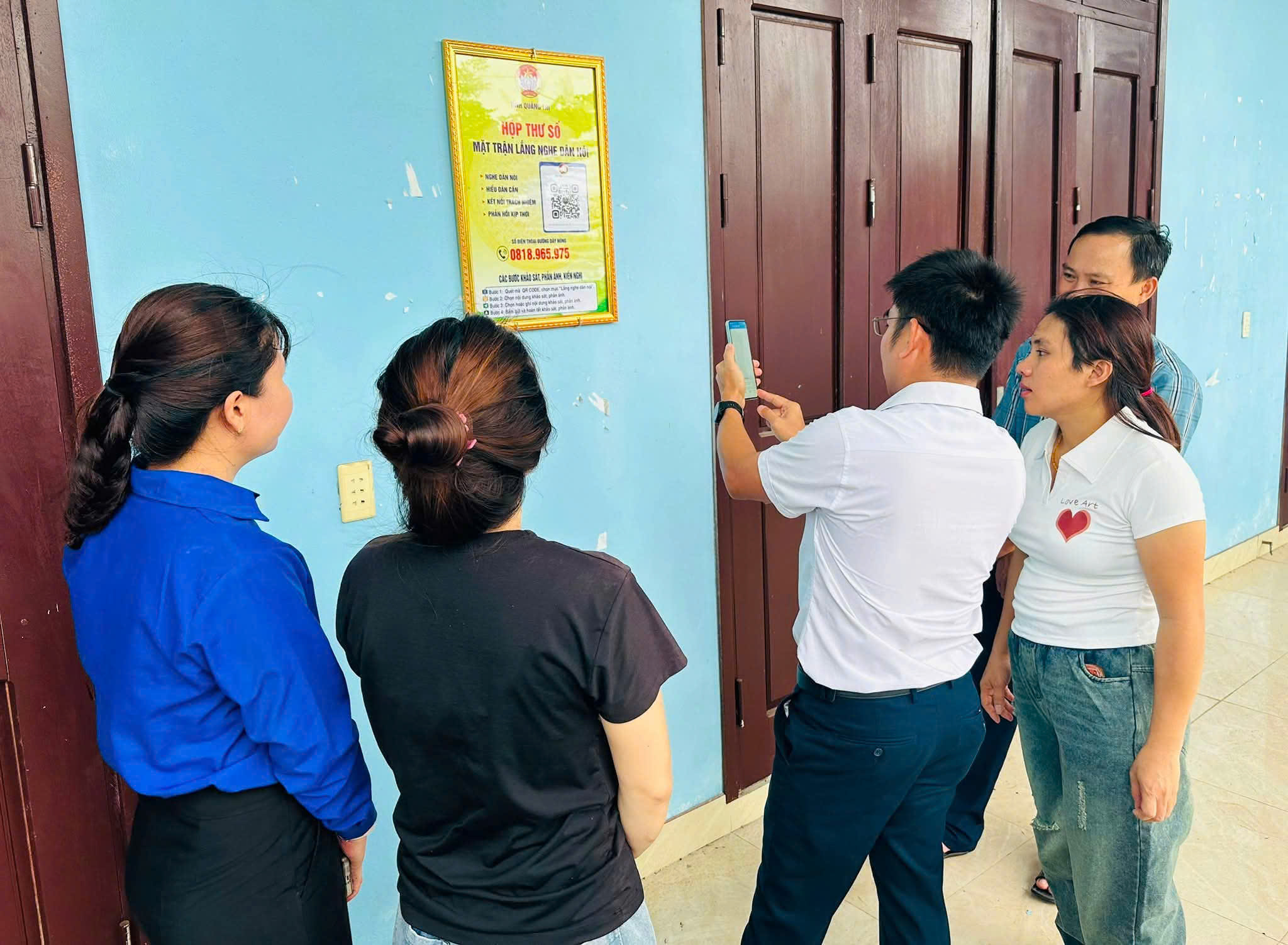 Cán bộ Mặt trận hướng dân người dân quét mã tại hộp thu số để gửi ý kiến tham gia