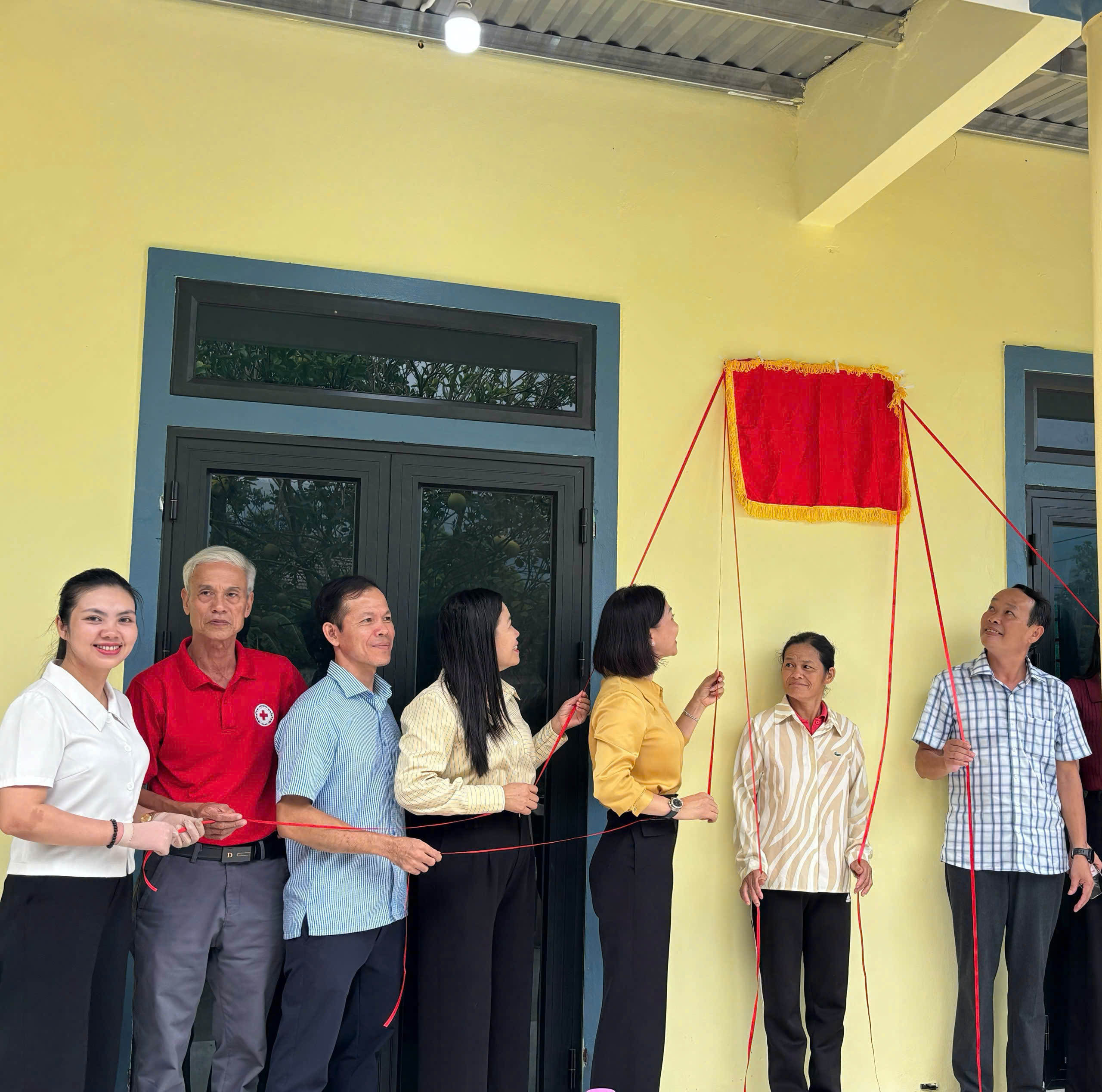 Các đại biểu thực hiện nghi thức kéo băng khánh thành Nhà Đại đoàn kết cho hộ bà Nguyễn Thị Dưng, Tổ dân phố Thuận Phước